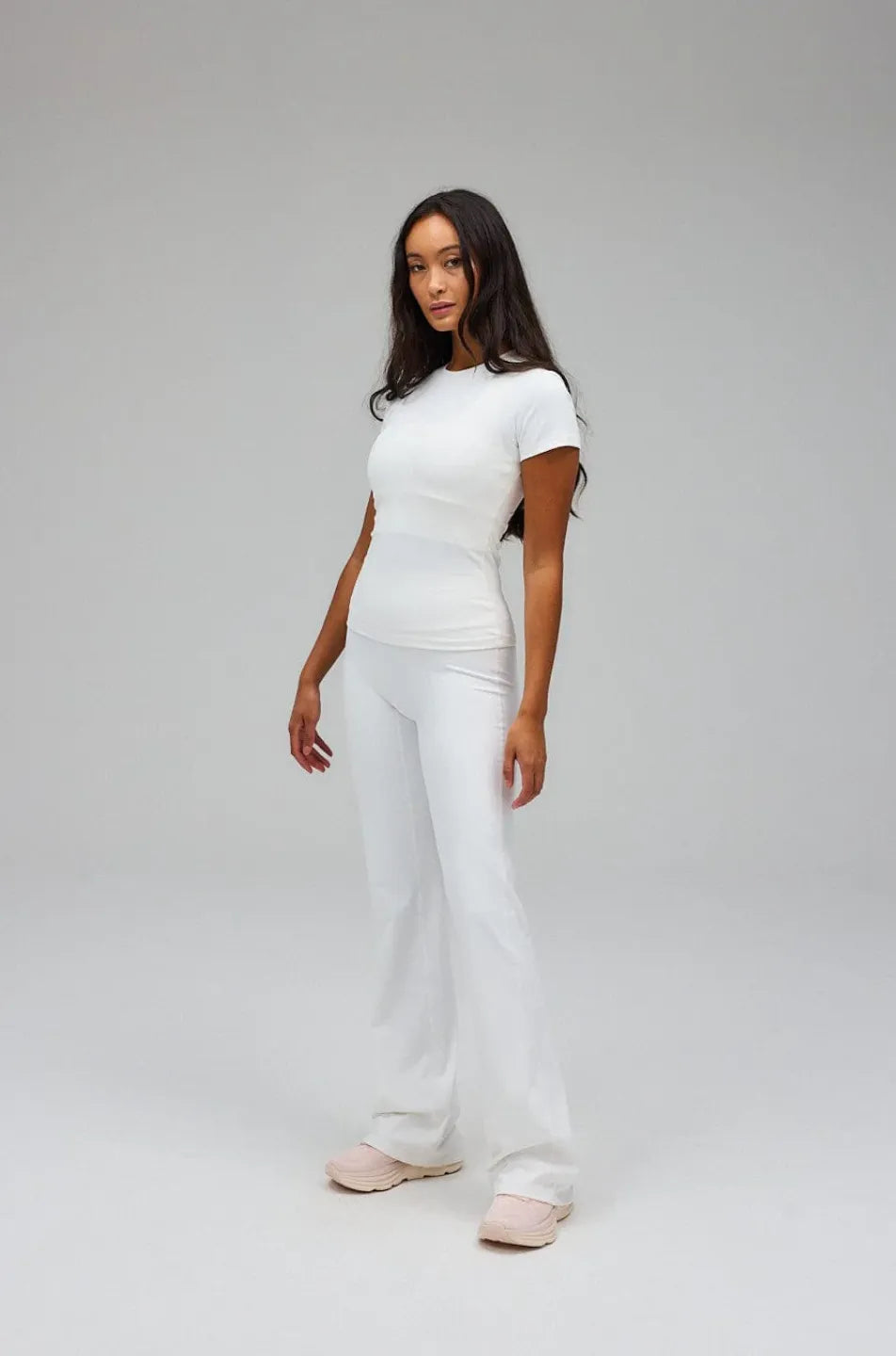 Person wearing a white t-shirt and pants on a grey background