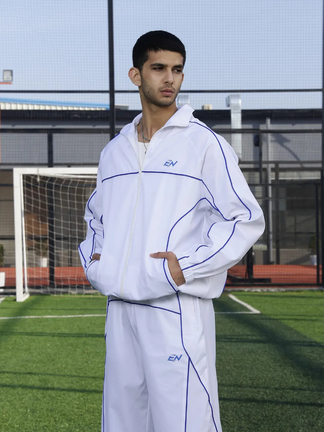 Person wearing a white sports jacket  with blue accents on a sports field.