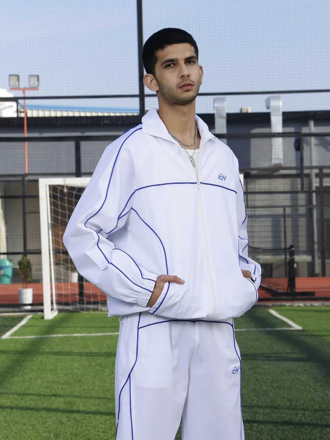Person wearing a white sports jacket with blue accents on a sports field