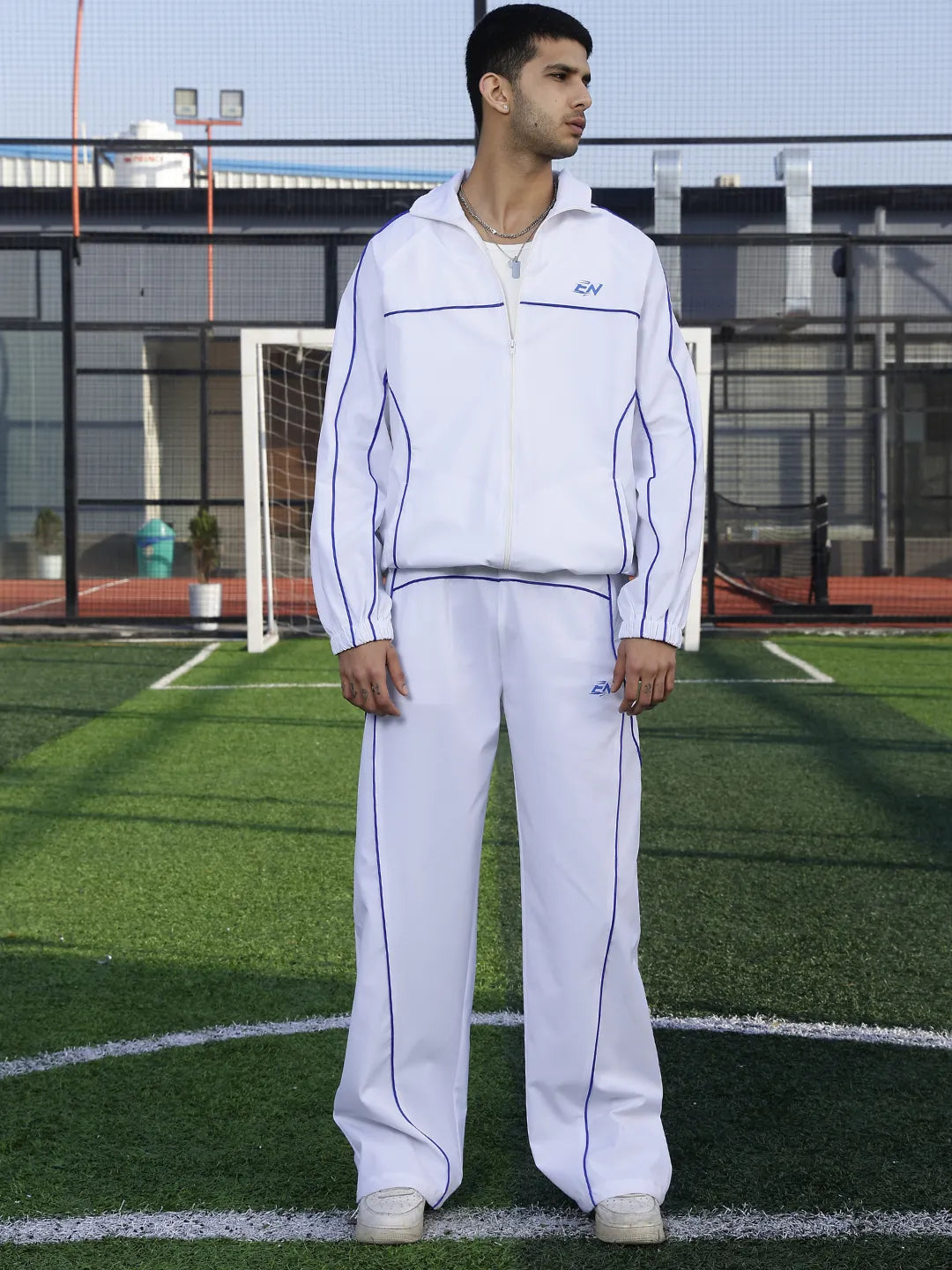 Man wearing a white sports outfit with visible branding on a sports field.