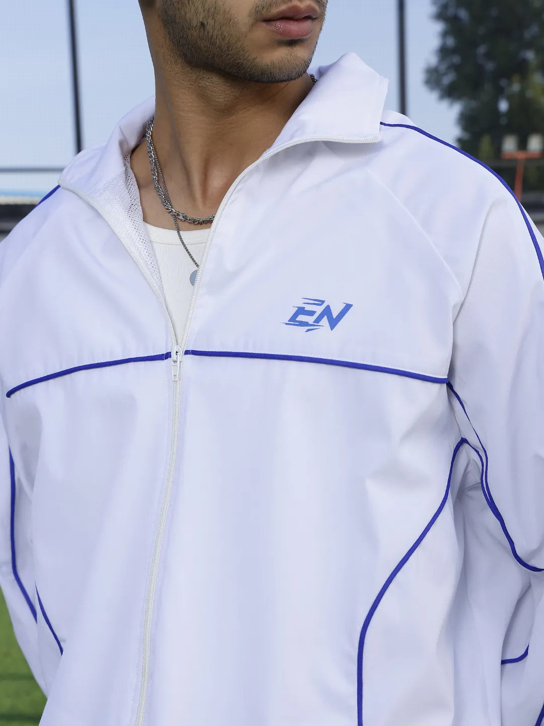 White sports jacket with blue accents and a logo on a person outdoors