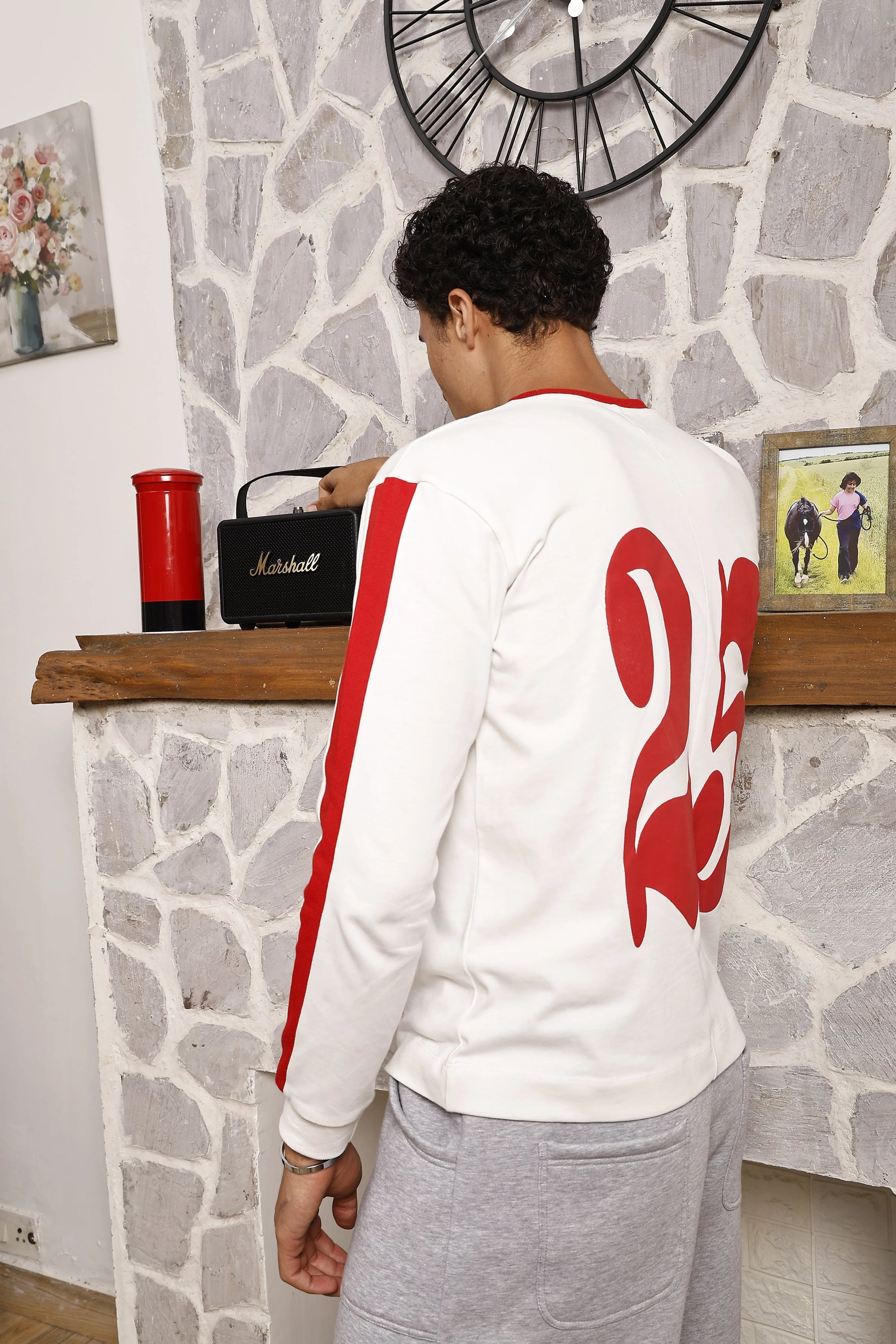 Person wearing a white long sleeve sports t-shirt with red design 