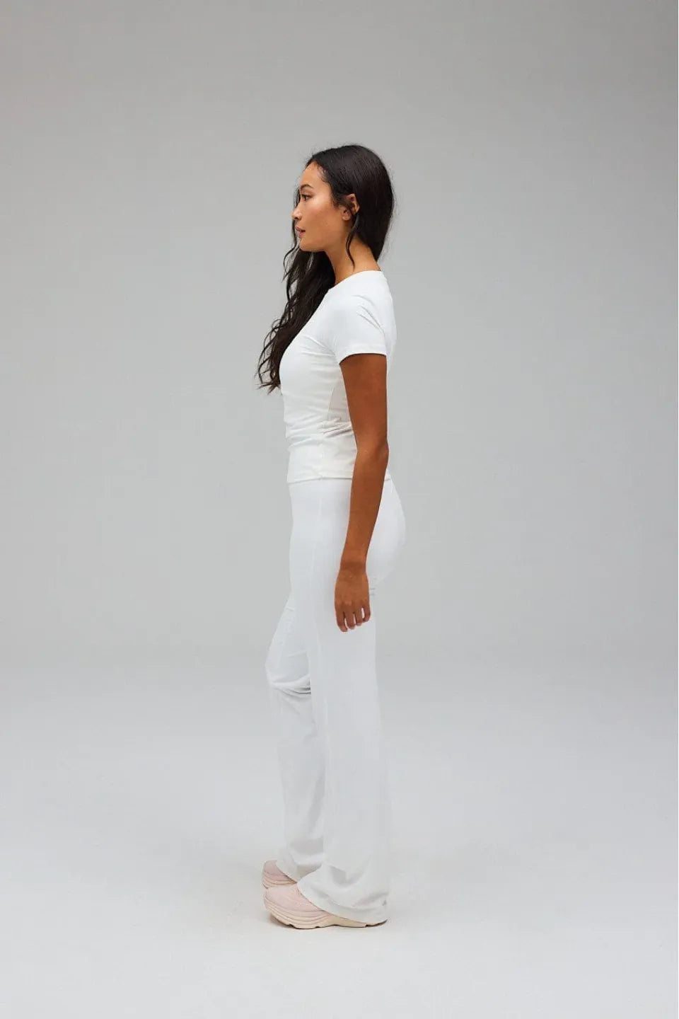 Woman wearing a white outfit standing against a grey background