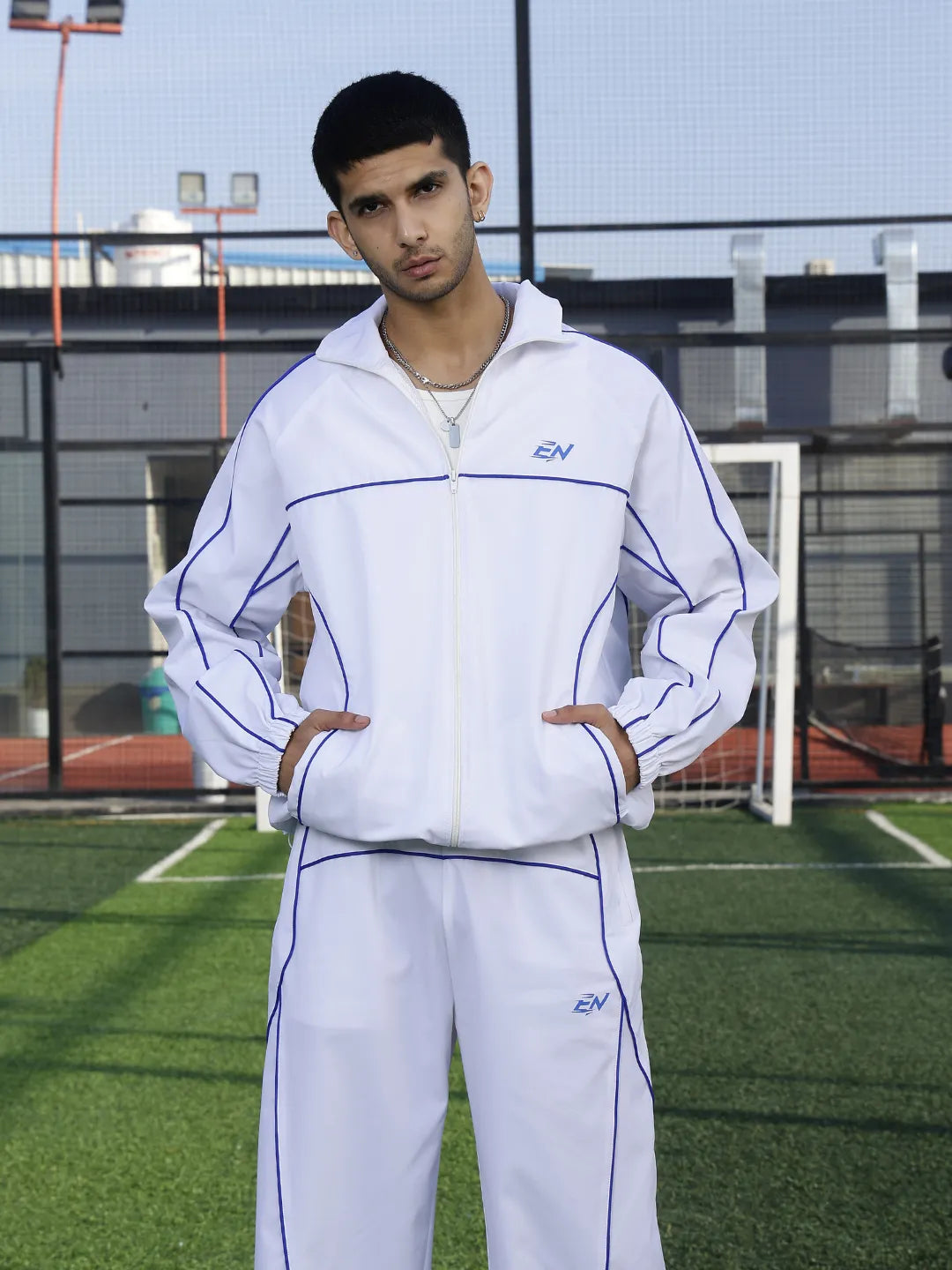 Person wearing a white tracksuit with branding on a sports field