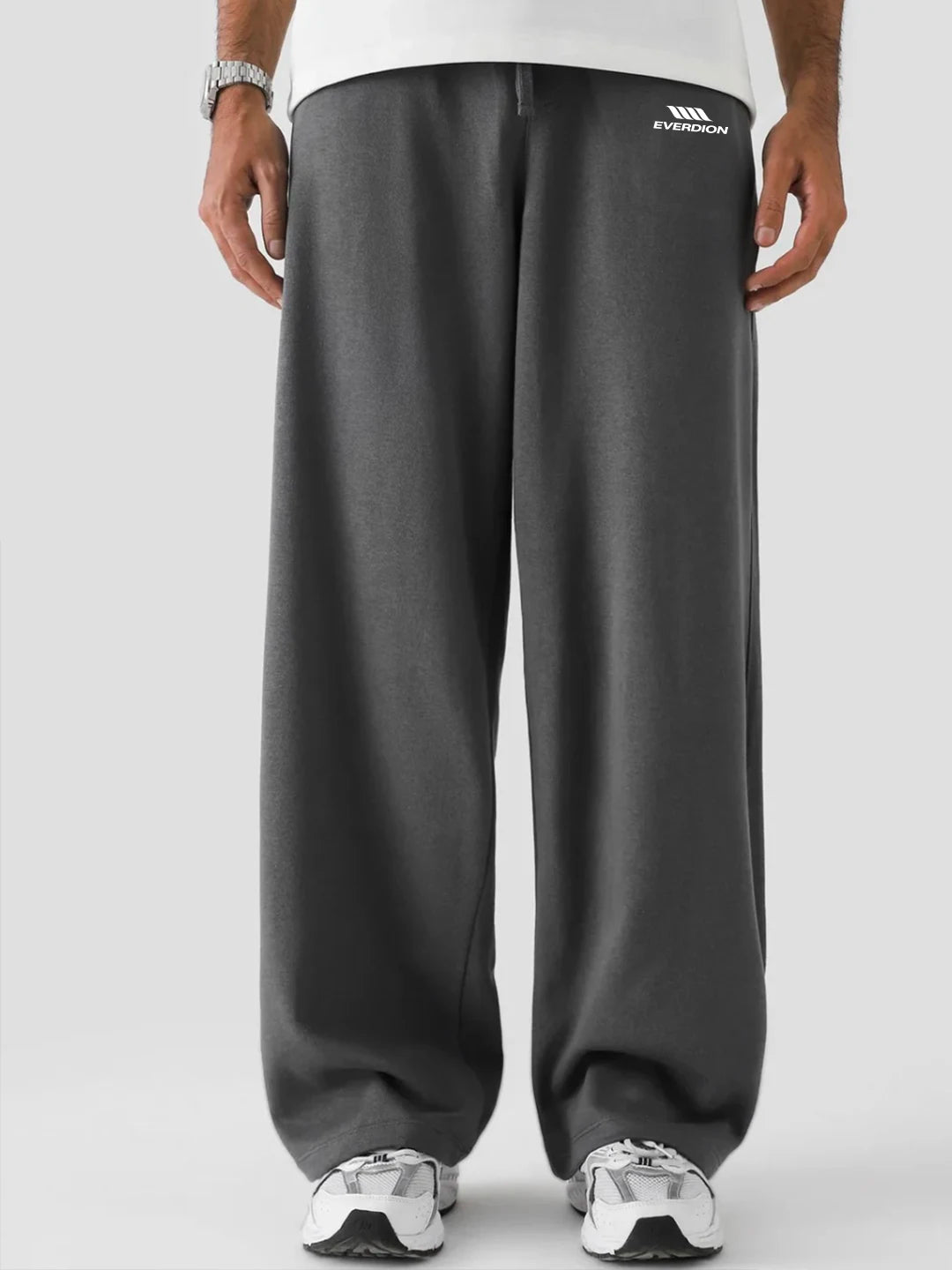 Person wearing grey sweatpants with a brand logo on a light grey background