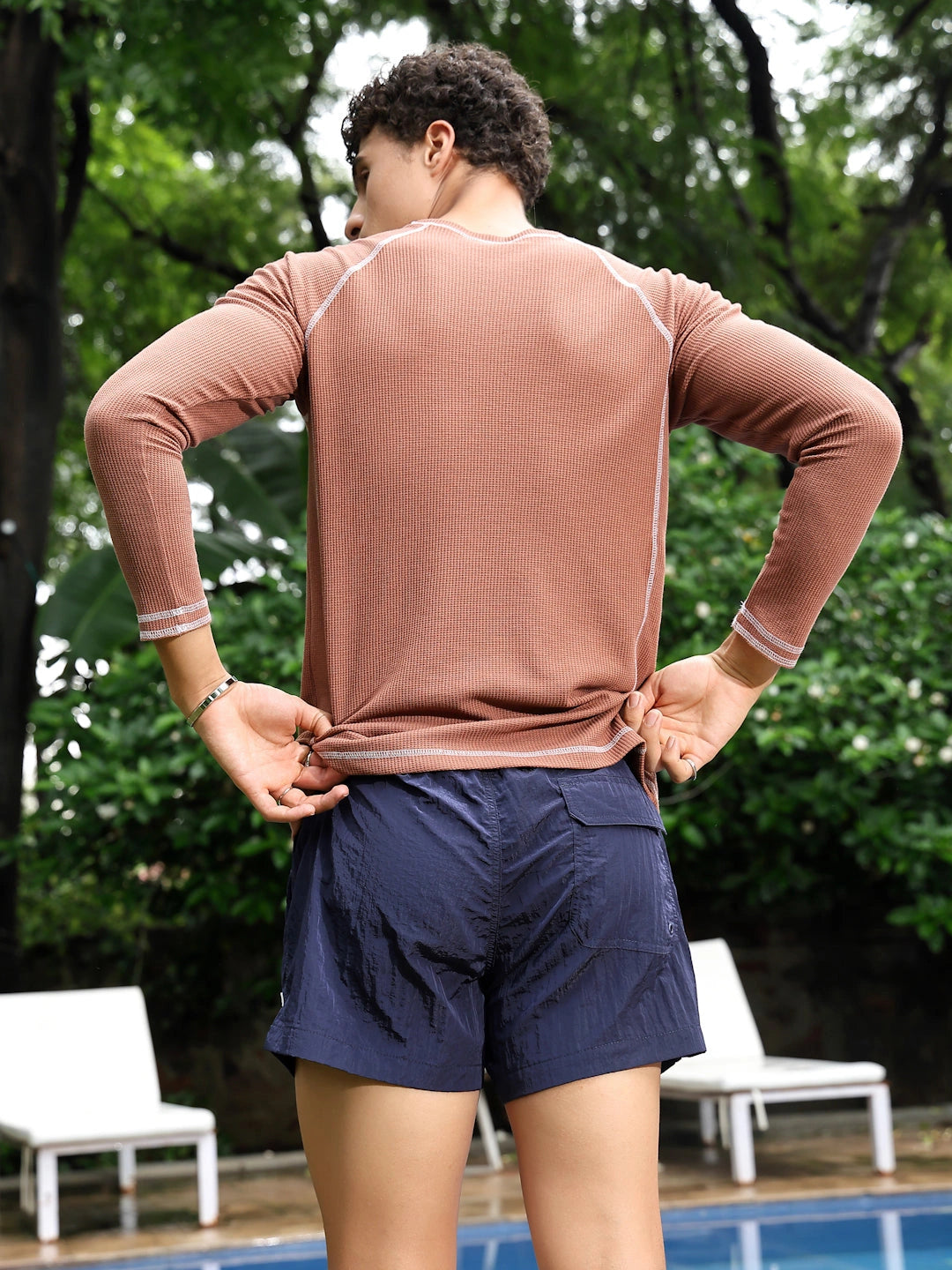 Person wearing a long-sleeve brown top and navy shorts 