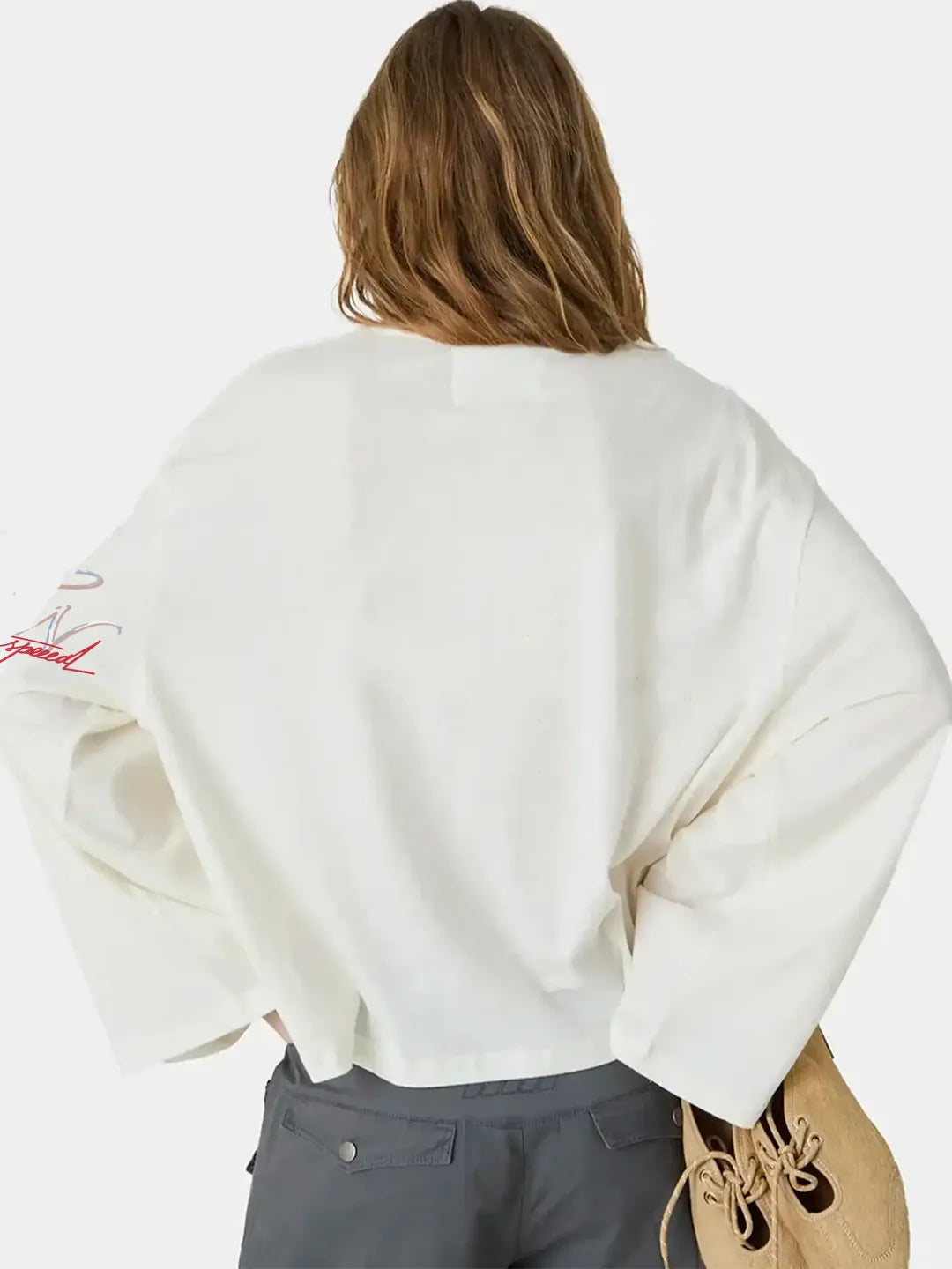 Person wearing a white oversized t-shirt with a logo on the back, standing against a plain background