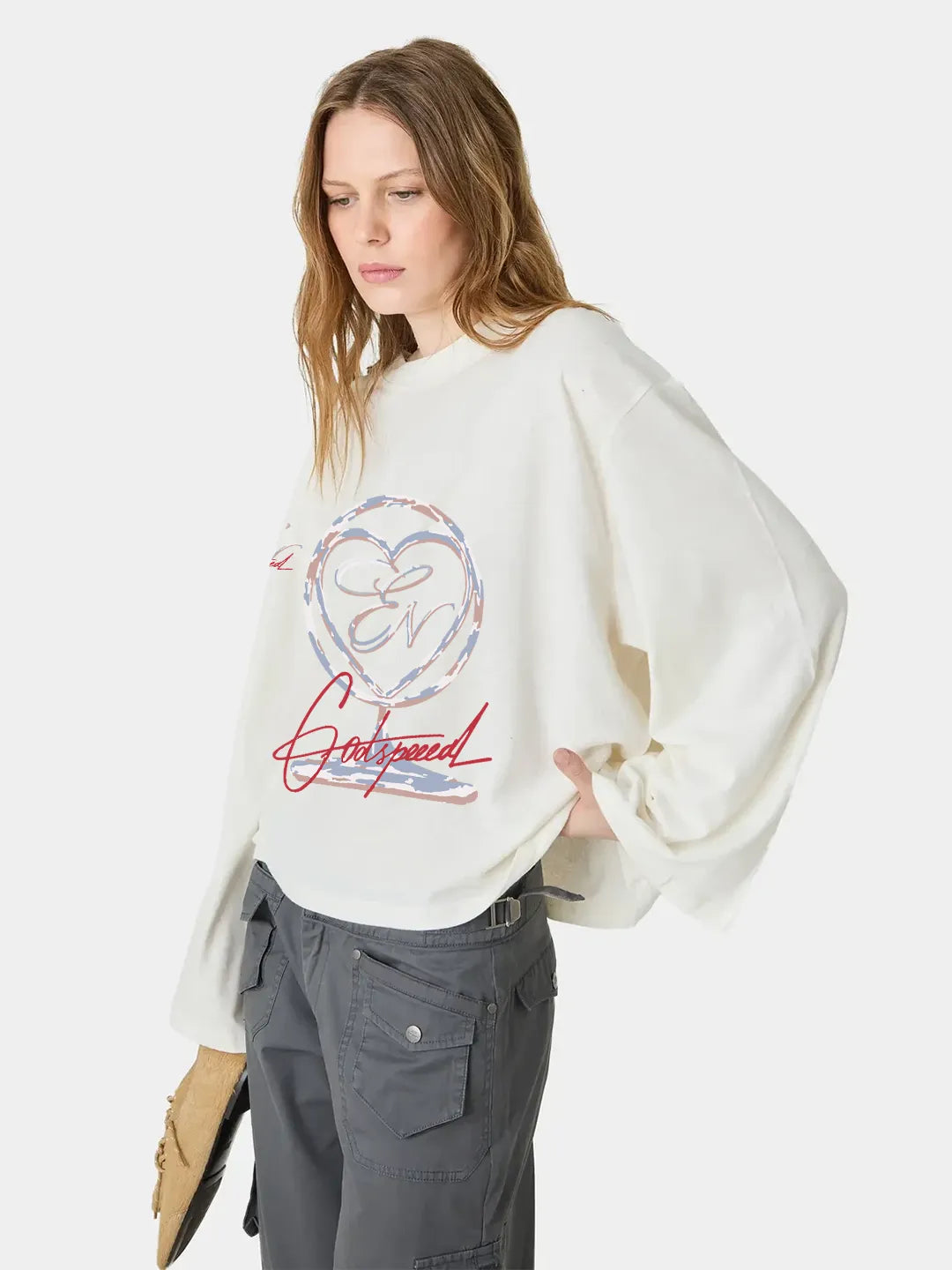 Woman wearing a white long sleeve oversized t-shirt with a graphic design on a white background