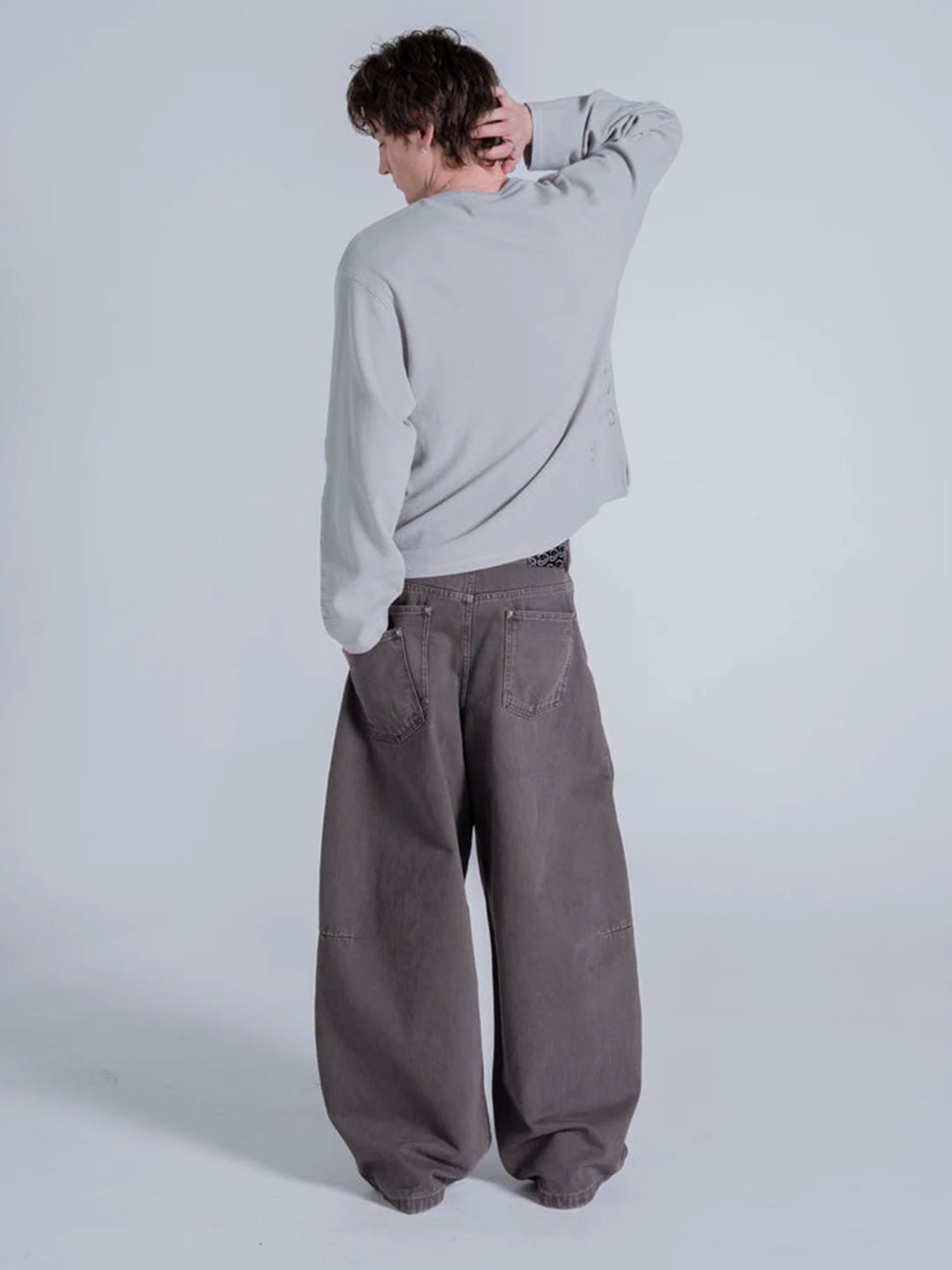 A model wearing a light grey long-sleeve t-shirt and very wide-leg dark grey baggy pants