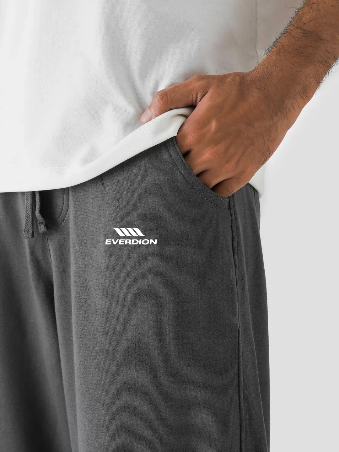 Grey pants with Everdion logo worn by a person, on a plain background