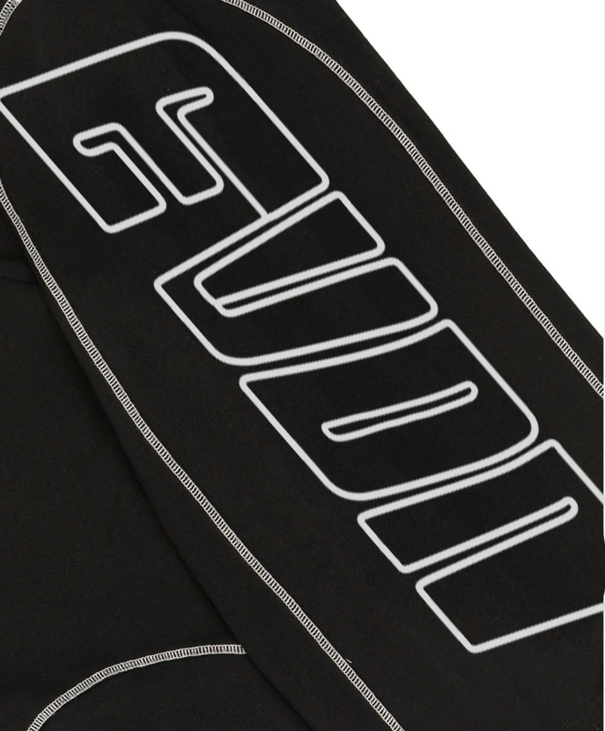 Close-up of a black sweatpants featuring a large white outlined graphic logo and white contrast stitching.