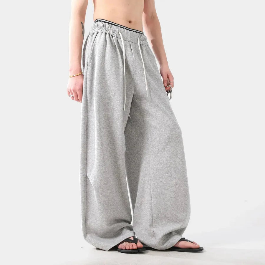 Person wearing grey wide-leg pants on a white background